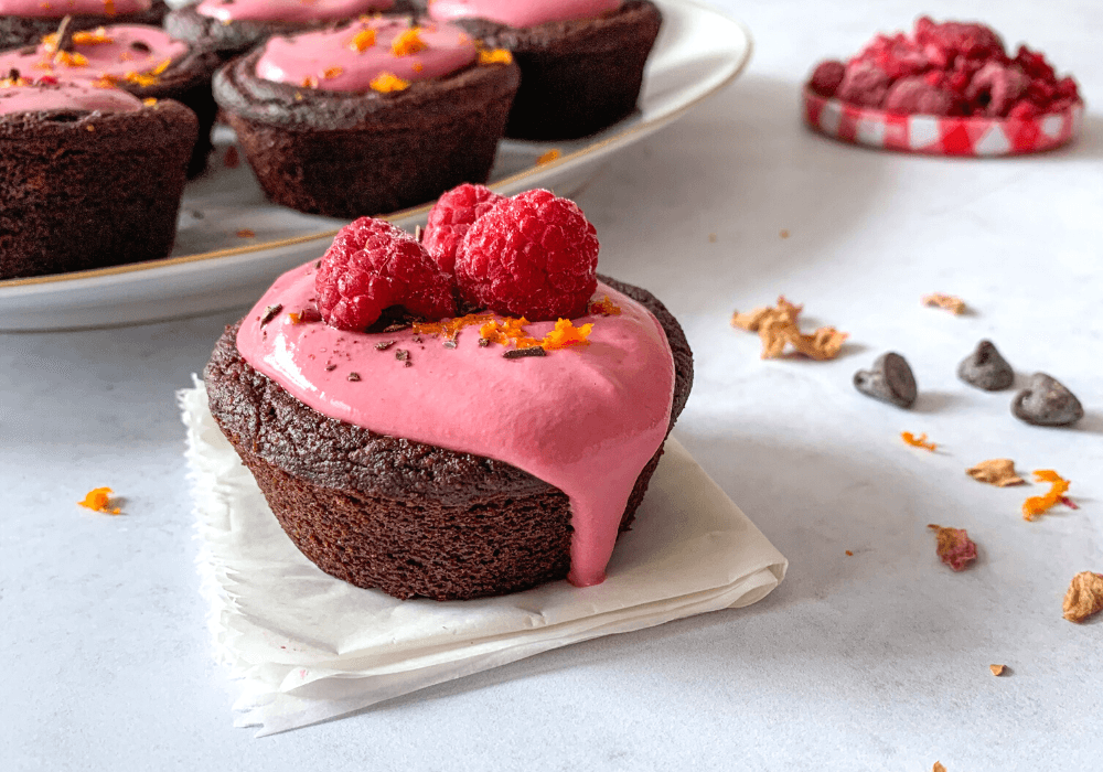 This image shows a close up of a single cupcake with the raspberry orange frosting dripping down one side.