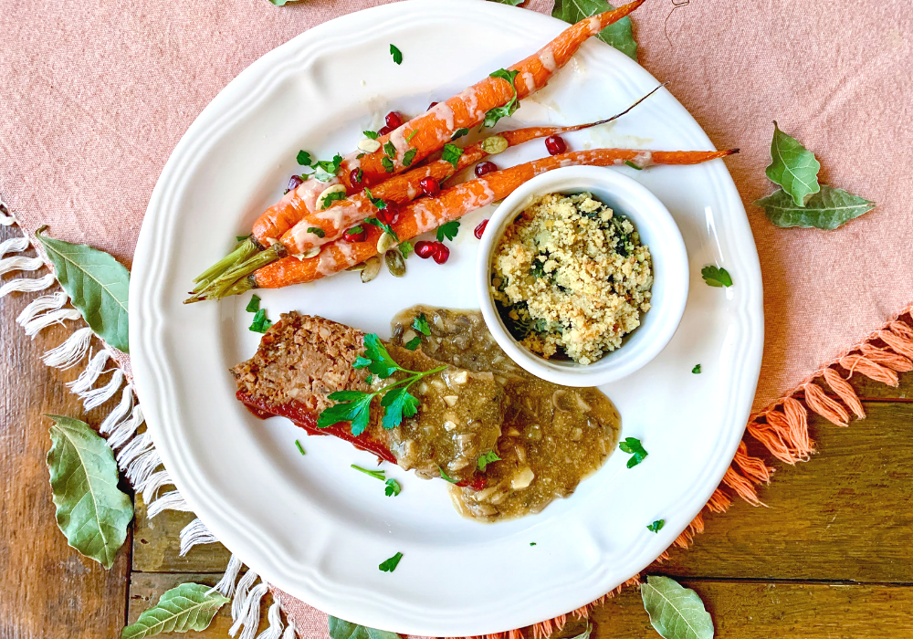 This image shows a slice of the best meatless meatloaf with mushroom gravy, roasted carrots, and kale gratin. All plant-based and gluten free.