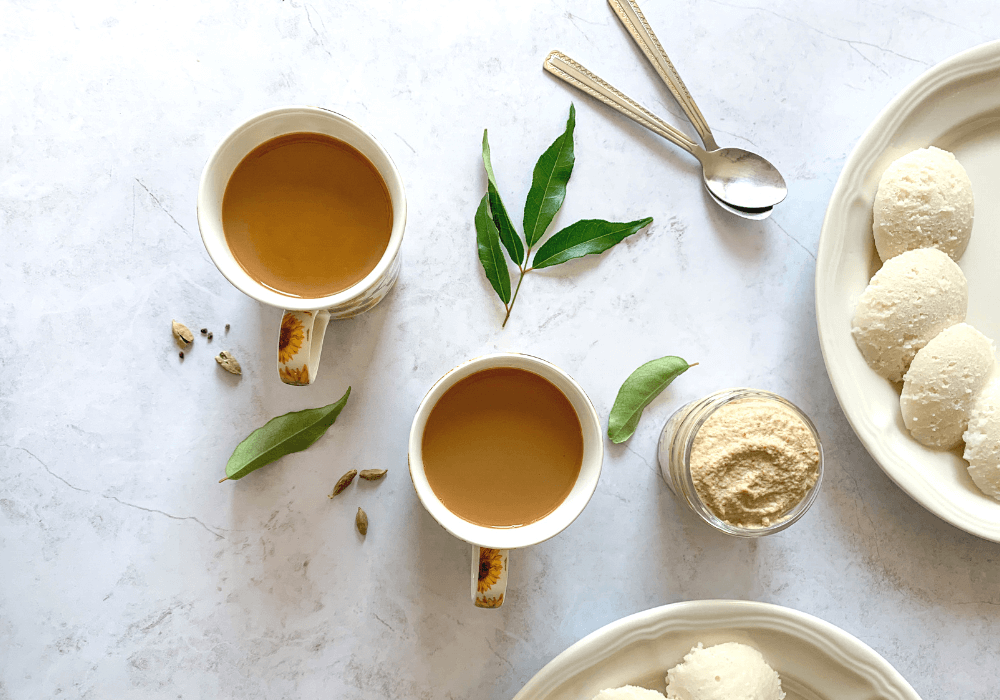 This image shows mugs of warming indian masala chai with a traditional indian breakfast