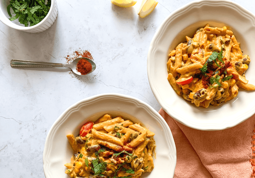 This image shows two bowls of creamy plant-based fiesta mac and cheese packed with whole plant foods and flavor. This meal is an example of the types of meals one can make with meal planning.