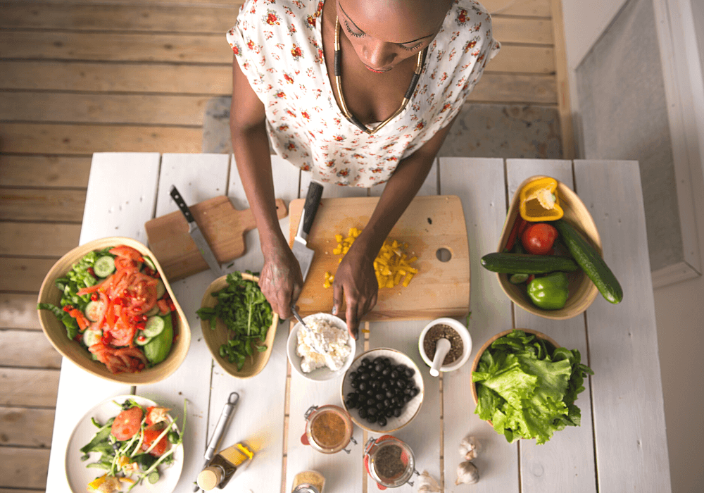 This image show a woman with a mise en place of various ingredients she's using to assemble a salad.