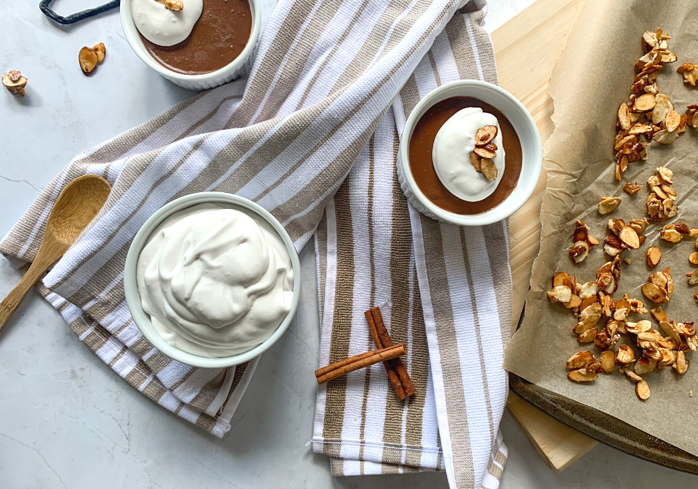 This image shows the Mexican Chocolate Pots de Creme with coconut whipped cream and candied almonds on top, plus a tray of candied almonds on the side.