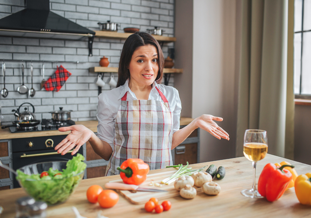 This image shows a woman in her kitchen confused and overwhelmed about what and how to cook plant-based.
