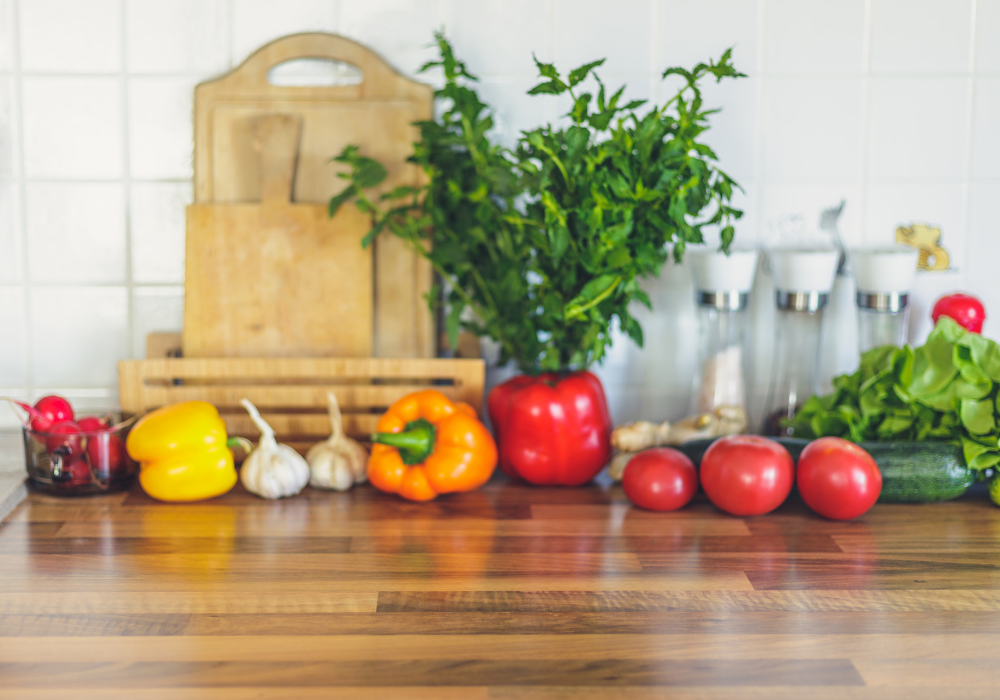This image shows part of a clean kitchen with abundant fresh fruit and vegetables on the counter.