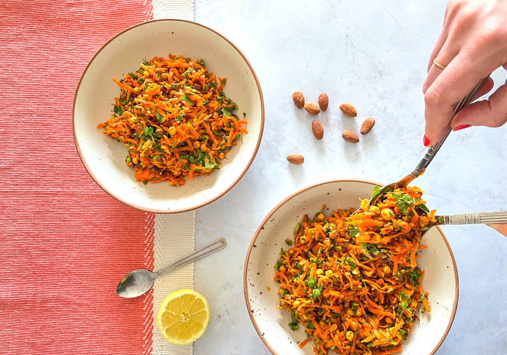This image shows two bowls of Spicy Carrot Salad with Crunchy Masala Chickpeas being plated. 