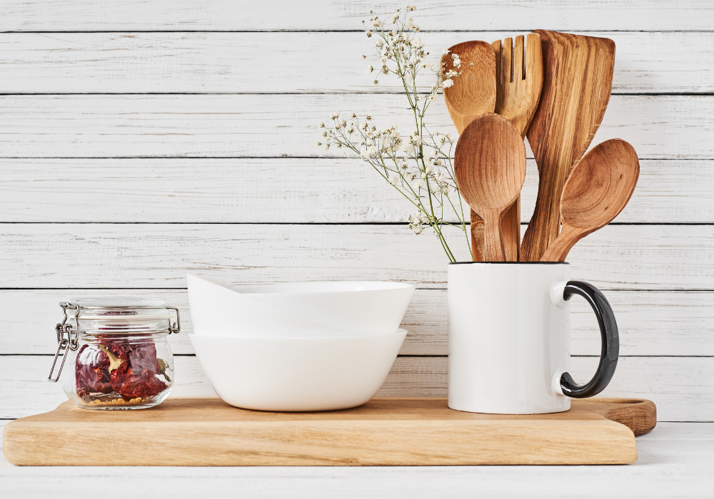 This image shows a kitchen counter with some key tools for a plant-based kitchen including wooden cooking utensils and a sturdy wooden cutting board.