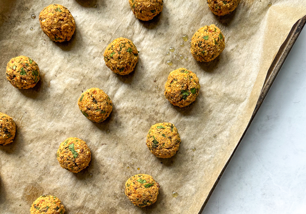 This image shows a close up of plant-based meatballs on a baking tray.