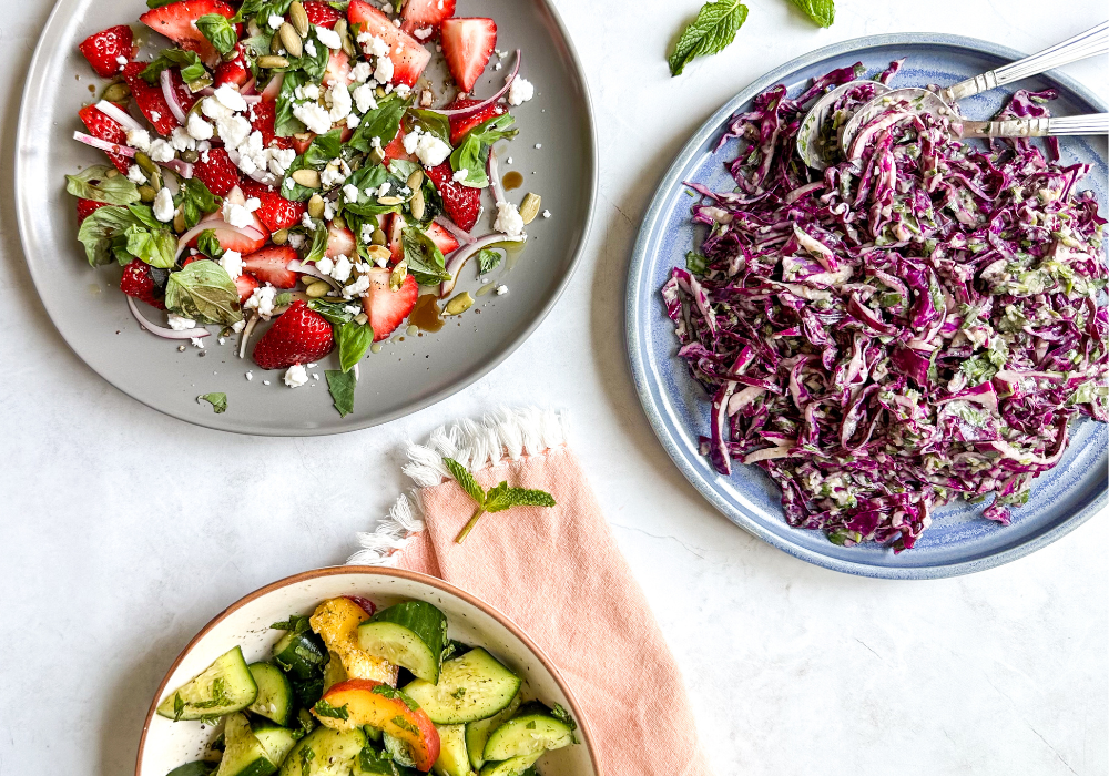 This image show the three quick and easy summer salads on platters on a light background with an orange napkin.