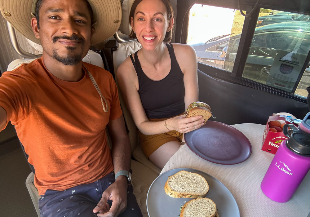 Image from our plant-based camping trip, showing us eating our packed sandwich lunch at the dinette table in our campervan.