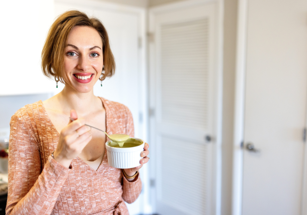 This image shows a woman following a plant-based diet eating something green with a spoon.